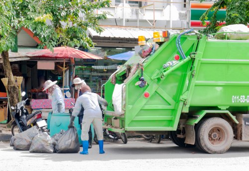 Workers wearing PPE during skip loading showing insured waste company safety practices